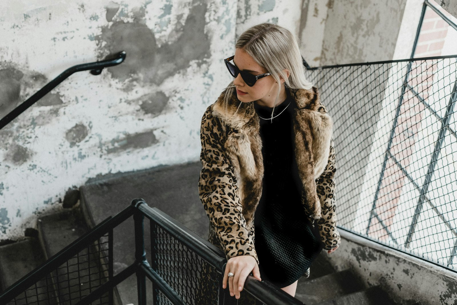 Woman in a black and brown animal print coat walking down city stairs