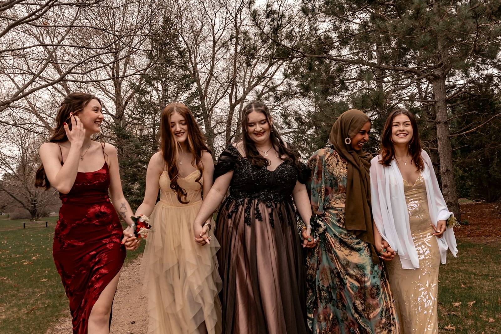 Women in formal dresses holding hands outdoors — what to wear to a fall wedding as a guest