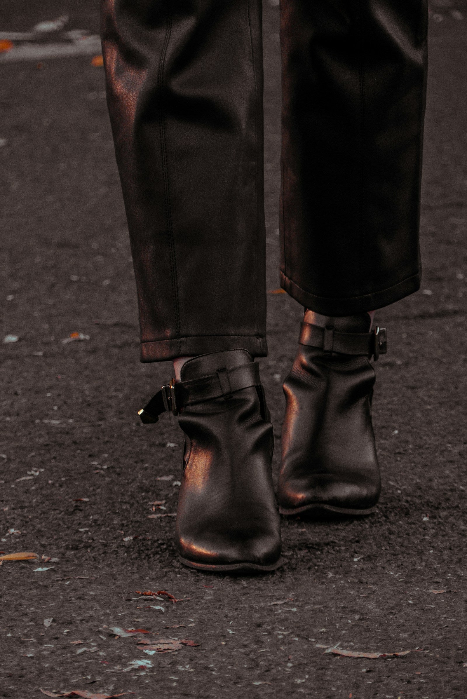 Wide-leg trousers over leather boots on a leaf-covered street