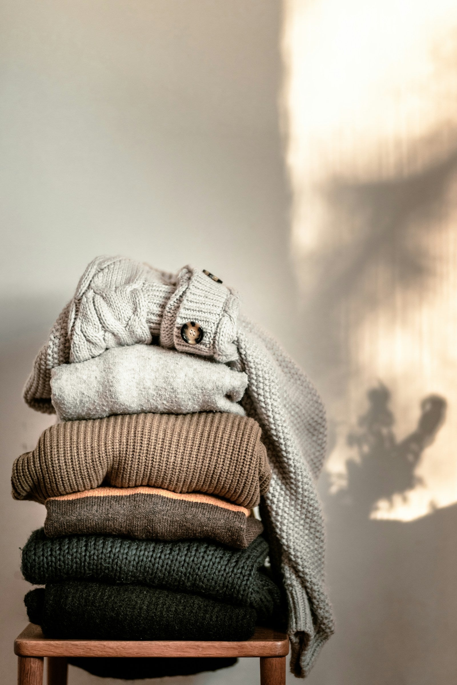 Stack of folded knitwear on a wooden chair