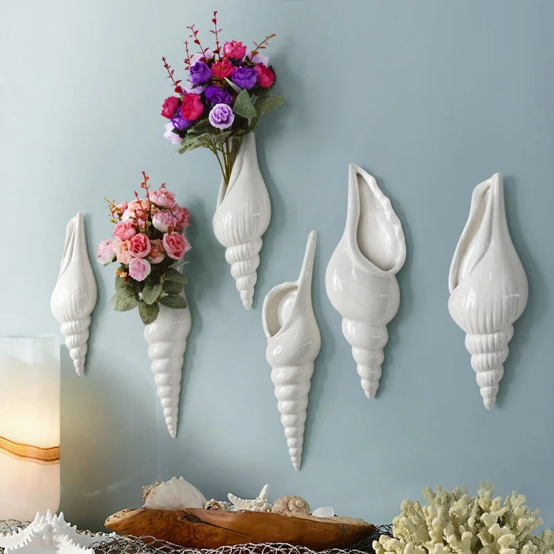 Nautilo shell vases on a blue wall with flowers
